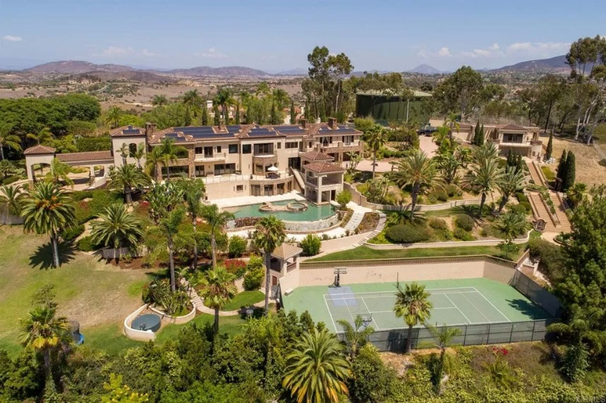 The funded Rancho Santa Fe estate compound seen from the air: tile-roofed buildings, terraced gardens, a pool and a tennis court.