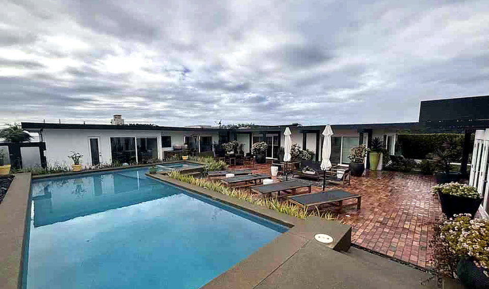 The funded Corona del Mar residence: a single-story modern home around a pool terrace under a coastal sky.
