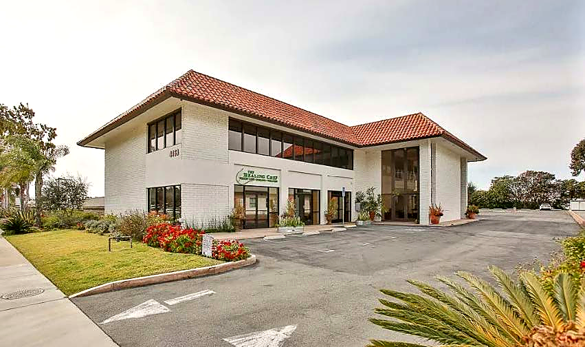 The funded Newport Beach property: a white two-story commercial building with a red tile roof and a landscaped parking court.